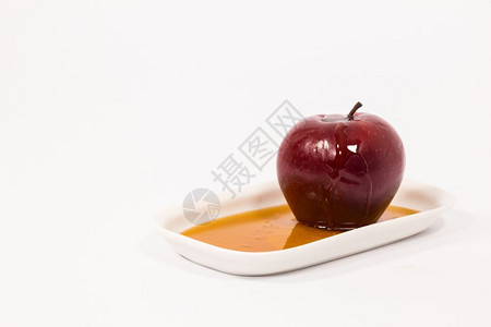 红色苹果白盘子上有一滴蜂蜜在白色背景上孤立着蜂蜜犹太新年的符号RoshHashanah图片