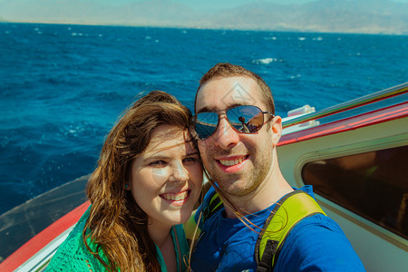快乐的情侣在船上航行带着智能手机或相自拍图片