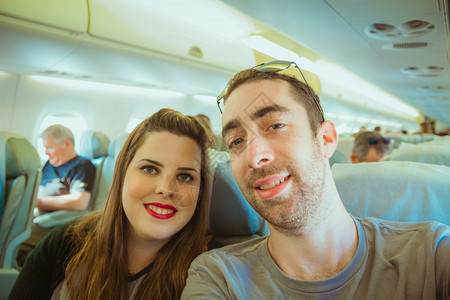 情侣在飞机上带着智能手机玩自拍图片