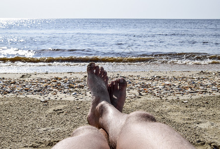 海滩背景上男人的腿一个人躺在沙滩上的一条小路上休息框架中的腿海滩背景上男人的腿一个人躺在沙滩上的一条小路上休息框架中的腿图片