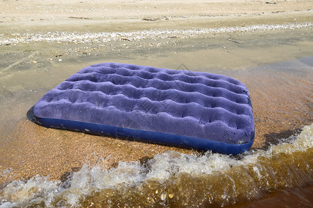 在池塘中游泳的蓝色充气床垫在海滩上游泳的蓝色充气床垫背景图片
