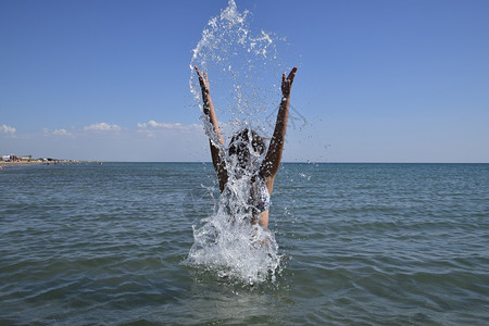 她喷洒在海水中黑发女孩和洗澡享受海的滋味图片