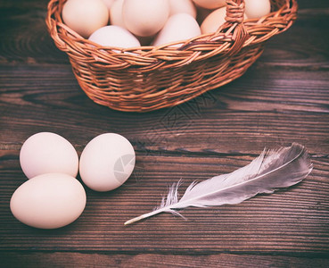 近视图竹篮里的鸡蛋和桌上的羽毛图片