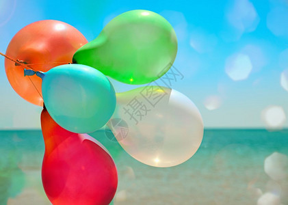 多彩气球在太阳下飞向海面图片
