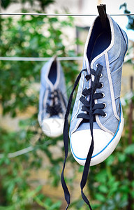 挂在木板后绳子上的旧蓝色运动鞋图片
