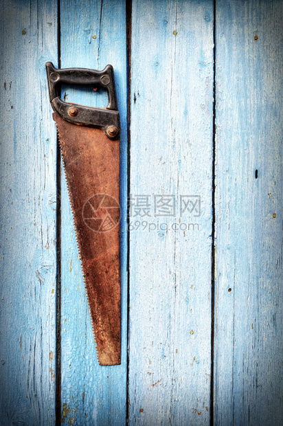 旧生锈的手锯挂在蓝色木墙上古老的铁锯图片