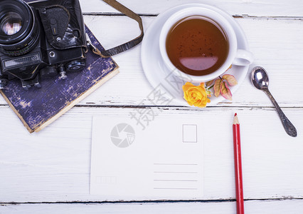 白色圆杯黑茶配有碟子的白杯旁边是旧电影摄像头背景图片