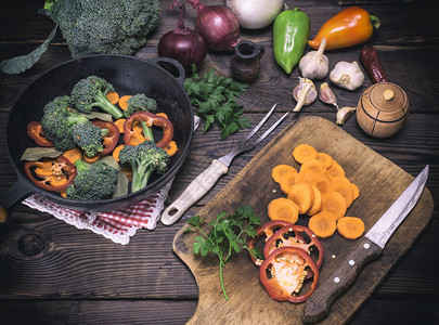 木制厨房板上的新鲜胡萝卜花椰菜和红辣椒旁边是圆面铁煎锅旧式图片
