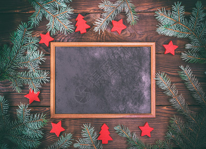绿色树枝和新年装饰品中间褐木背景上的空黑框图片