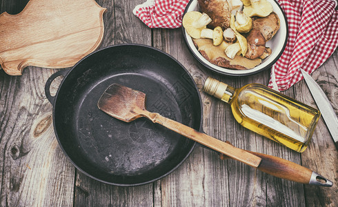 新鲜可食用野生蘑菇橄榄油和黑圆铁煎锅最高视图图片