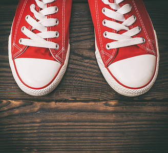 一对红色的纺织运动鞋上面是棕色木制背景的白鞋带顶视图图片