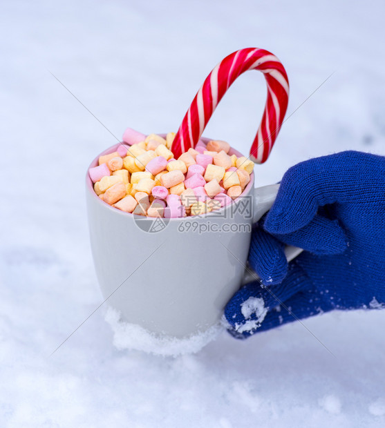 灰色杯子手拿着热巧克力和棉花糖与白雪相对