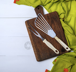 棕色木板上的厨房老旧叉子和骨白桌上的绿毛巾左边空图片