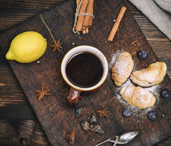 棕色陶瓷杯木板上含黑茶和牛角面包顶视图棕色陶瓷杯黑茶和牛角面包图片