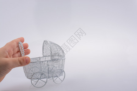 由白色背景金属制成的手持玩具婴儿搬运车图片