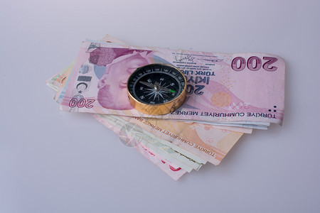 白色背景指南针旁的土耳其里拉钞票图片