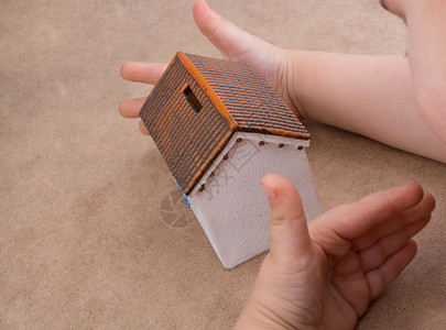 小模特儿房子和手浅棕色背景的手背景图片