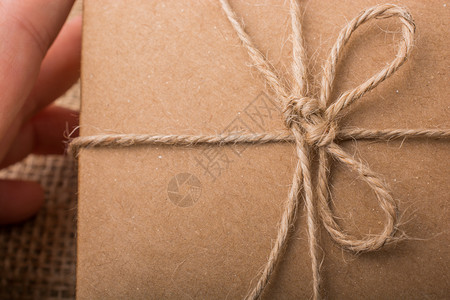 手拿着一盒棕色的礼包放在麻布上图片