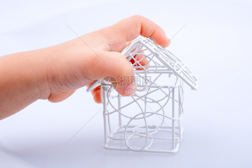 由白色背景的手边金属条组成的小模范房屋图片
