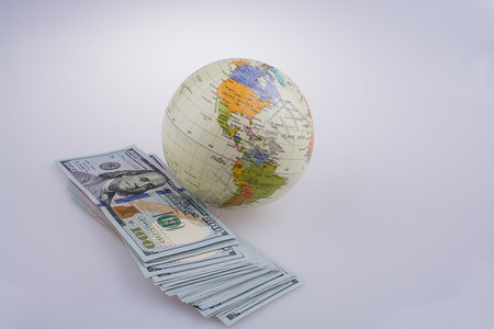 白色背景的模型地球旁边美元钞票图片