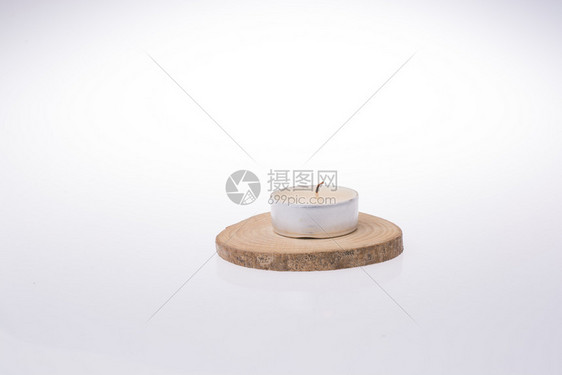 在白色背景的一块木头上放置的蜡烛图片