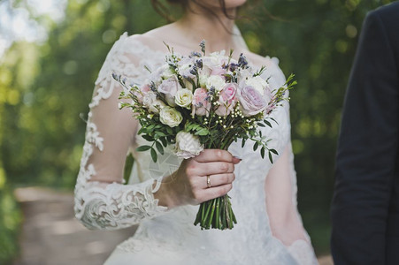 新娘手里拿着一束鲜花手柄脆弱新娘手里拿着一束美丽的花沿着绿地走来去背景图片