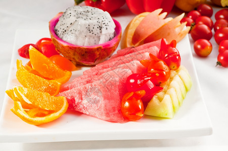 黄色新鲜水果含有西瓜橙苹果和樱桃西红柿的新鲜水果皮塔亚或龙混合盘背景