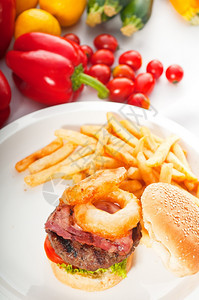 美国经典汉堡三明治配洋葱环和薯条背景有新鲜蔬菜在PORTOFOLIO上更美味的食品图片
