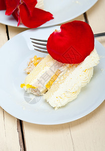 带红玫瑰花瓣的奶油芒果蛋糕背景图片