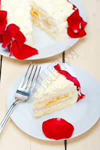 带红玫瑰花瓣的奶油芒果蛋糕高清图片