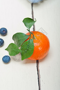 白色锈制木板上的橘子和蓝莓图片
