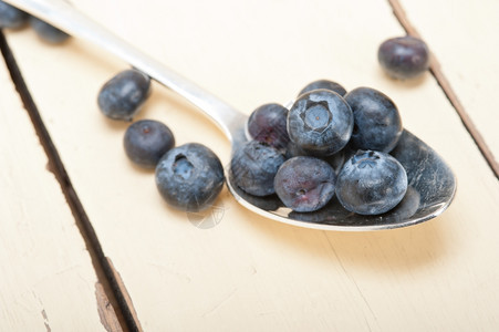 银汤匙上的新鲜蓝莓在白锈木制的桌子上图片