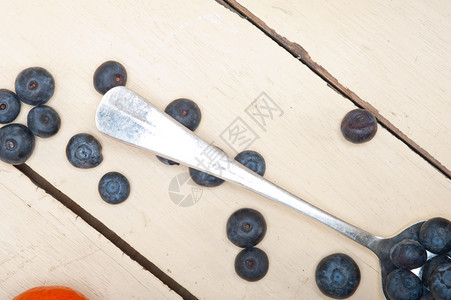 银汤匙上的新鲜蓝莓在白锈木制的桌子上图片