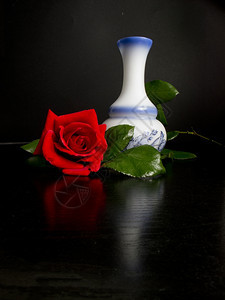 一个漂亮的红玫瑰花瓶装饰黑桌提示图片