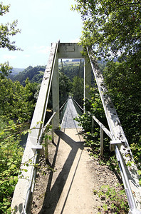 在河上架起有绿的窄悬吊桥图片