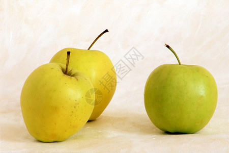涂漆背景上的三个黄色苹果图片