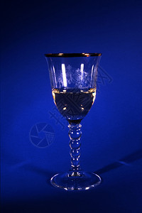蓝色背景上孤立的玻璃白葡萄酒图片