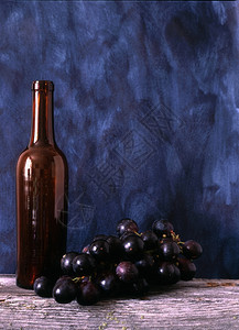 在涂漆背景上孤立的酒瓶和葡萄图片