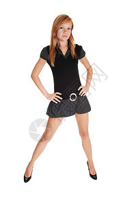 一个穿着黑色短裙和高跟鞋的年轻美女站在工作室里双腿张开图片