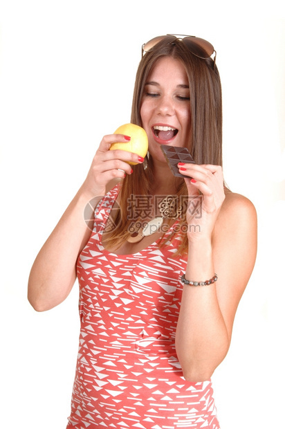身着粉红裙子和墨镜的年轻女子头部不能决定吃白底苹果或巧克力图片