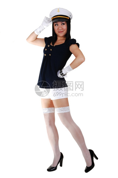 一个年轻的亚洲美女穿着水手制服白短裤长袜和手套穿着高跟鞋和水手帽站在工作室敬礼图片