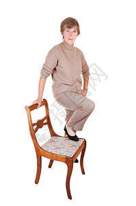 一位穿着衣服裤子和米色毛衣的女士穿着高跟鞋站在工作室的老椅子上图片