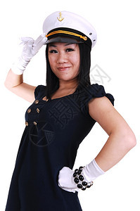 一个年轻的亚洲美女身着水手制服白套水帽站在工作室敬礼图片