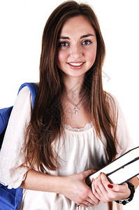 一个穿着米色上衣的漂亮少女和一个蓝色背包着她的肩膀和书本在她手里站工作室白背景图片