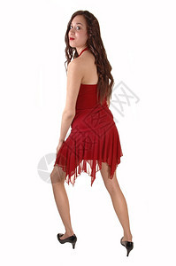 一个穿着红色礼服的年轻美女在工作室里笑着走来去为了白背景图片