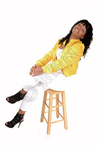 一位年轻的非裔美国女孩坐在椅子上穿着白色的紧身裤背着黄色的夹克图片