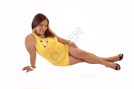 一个穿着黄色裙子的年轻可爱女人坐在地板上微笑着带红头发的镜图片