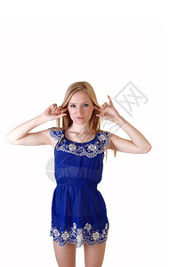 一个漂亮又瘦的年轻女人站在她的蓝色短裙和金发长耳朵里有手指工作室里有白种背景图片