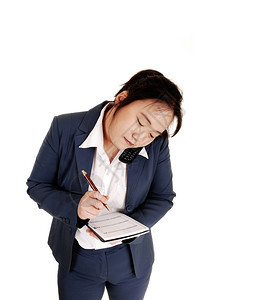 一位亚洲女商人在电话上说白种背景的时间里做笔记图片