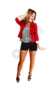 一个美丽的年轻女子站在白色背景穿着红的黑短裤和高跟鞋握着一只手在头上笑图片
